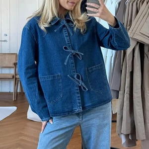 Détail d'une chemise en jean bleu foncé avec trois nœuds élégants et de grandes poches