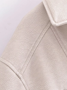Vue détaillée de la texture du similicuir crème avec coutures sur la veste de motard