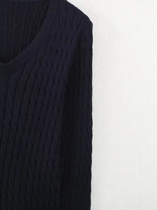 Gros plan sur la maille torsadée classique et le col en V d'un pull bleu marine foncé