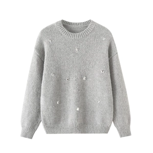 Detailed view of grey knit sweater featuring decorative sparkling rhinestones and ribbed cuffs