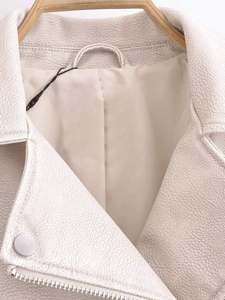 Gros plan sur le col d'une veste biker en similicuir crème avec texture grainée fine