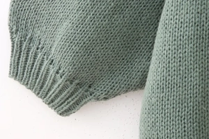 Detail of sage green knit sweater showing ribbed cuffs and thick premium texture