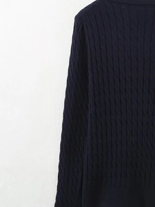Détail du pull en maille torsadée bleu marine montrant le tissage et la texture de l'ourlet