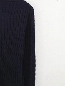 Détail de la maille torsadée épaisse sur un pull bleu marine foncé à col en V pour hiver