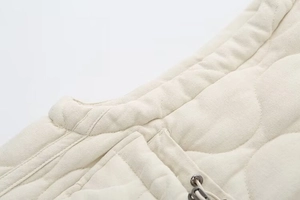 Detail of quilted vest neckline with adjustable drawstring and textured cotton fabric