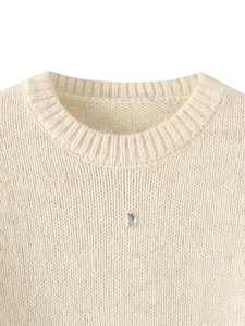 Detailed close-up of ivory knit sweater collar featuring a sparkling diamond rhinestone