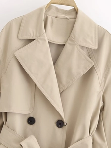 Detail of beige double-breasted trench coat with wide lapels and matching waist belt