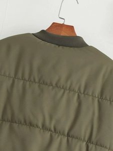 Detail der olivgrünen Steppjacke mit geripptem Kragen und horizontalen Steppnähten