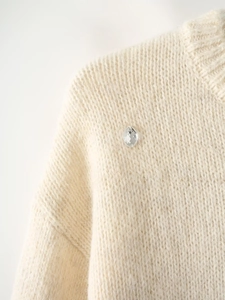 Detailed macro view of soft white mohair sweater fabric with a single sparkling crystal stone