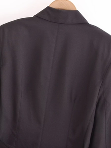 Detail view of the back seam and textured fabric of a chic black belted blazer dress
