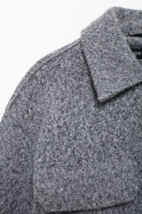 Detail of grey bouclé texture fabric with lapel collar and chest pocket on jacket
