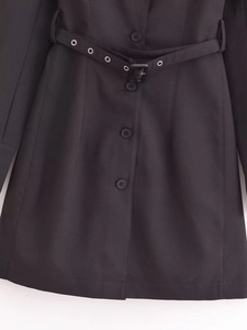 Detail of a black business dress with matching belt, metallic eyelets and round buttons