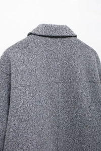 Close-up of the grey bouclé fabric texture and stitching detail on the short jacket