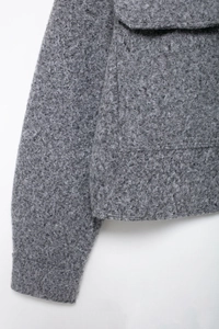 Close-up of dark grey bouclé jacket showing textured wool fabric and pocket detail