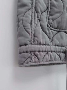 Macro view of grey quilted vest showing wave stitching and reinforced edge details