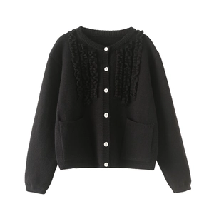 Detail of black knit cardigan with scallop ruffled trim and contrasting white buttons