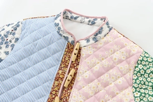 Detail of floral and striped patchwork quilted jacket featuring toggle buttons and stand collar