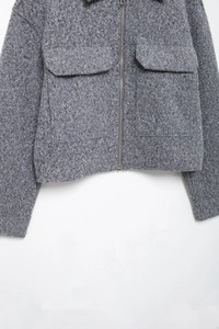 Detail of grey textured tweed jacket featuring silver zipper and large cargo pockets