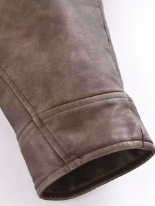 Gros plan du poignet d'une veste en simili cuir marron vintage avec coutures et texture