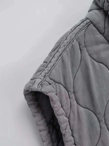 Macro detail of grey quilted vest showing shoulder seams and reinforced edging