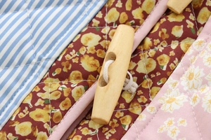Macro shot of patchwork quilted fabric with floral patterns and a wooden toggle button