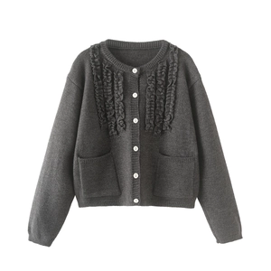 Close-up of dark grey knit cardigan featuring ruffle trim and contrast white buttons