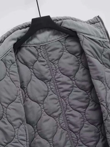 Detail of grey quilted vest with wave patterns, sturdy zipper and inner lining texture