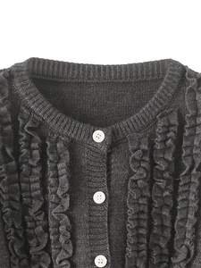 Close-up of black knit cardigan featuring ruffle trim details and white buttons