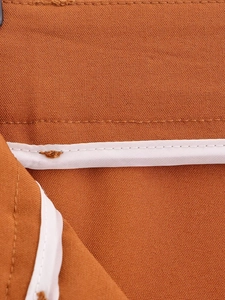 Detail shot of brown-orange fabric with white piping and neat stitching craftsmanship
