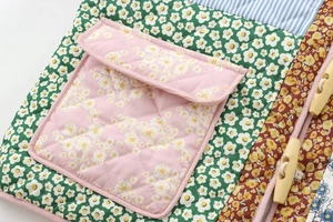 Close-up of floral quilted patchwork jacket featuring wooden toggle buttons and pink pocket