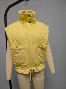 Detail of bright yellow quilted waistcoat featuring stand collar and drawstring pockets