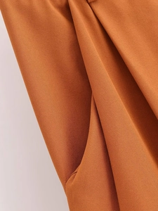 Detail of caramel high-waist pants showing high-quality side pocket and textured fabric