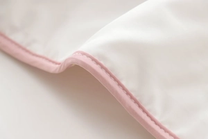 Detailed macro view of high-quality fine stitching and pink binding on white quilted fabric