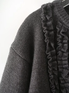 Close-up of charcoal gray knit cardigan featuring ruffled edges and textured fabric
