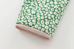 Detailed close-up of green quilted floral cotton jacket with pink piping and daisy patterns