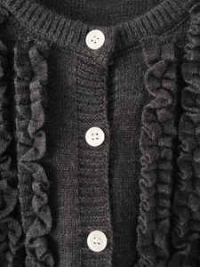 Close-up of dark grey knitted cardigan with white buttons and ruffled scalloped edges