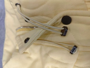 Detailed close-up of yellow quilted vest showing drawstring toggles and metal zipper hardware