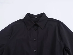 Close-up of black shirt collar detail with buttons and small size tag on plain fabric
