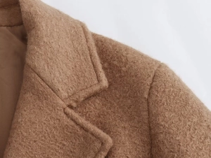Detailed close-up of textured faux shearling wool coat featuring classic lapel and stitching