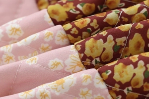 Detail of diamond-quilted fabric featuring pink and burgundy floral patchwork patterns