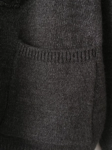 Close-up of knit texture and ribbed pocket detail on a charcoal grey cardigan