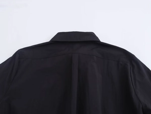Close-up of black midi dress showing shoulder yoke and back box pleat detail