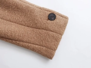 Close-up of camel wool blend fabric texture with a black resin button on winter coat