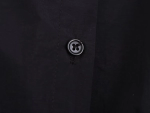 Detailed macro view of black resin button and secure stitching on the midi dress fabric