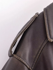 Détail de la veste en similicuir vintage montrant les épaulettes et le bouton pression