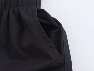 Detailed macro view of the elastic pleated waist and side pocket on this black midi dress