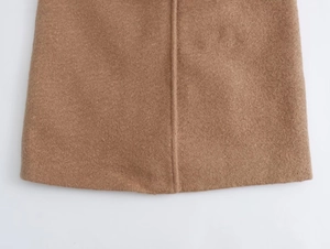 Detail of camel wool coat hem showing high-quality stitching and textured fabric