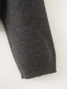 Detail of dark grey knit cardigan showing ribbed cuffs and premium textured wool fabric