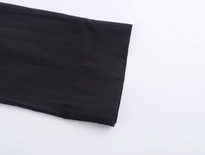 Detailed macro shot of the neat flat-seam stitching on black matte fabric dress sleeves