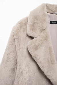 Close-up detail of light brown faux fur coat showing lapel collar and brand label on lining